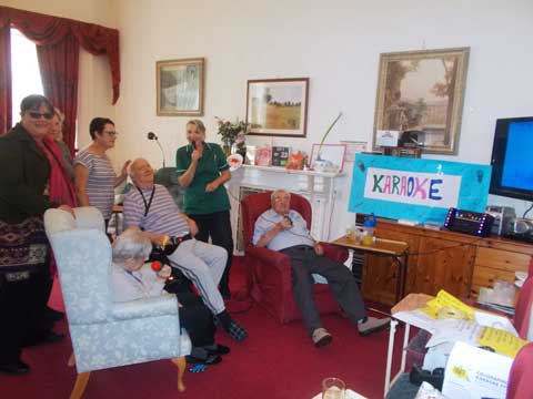 Karaoke group having fun with friends and relatives with staff joining in as invited